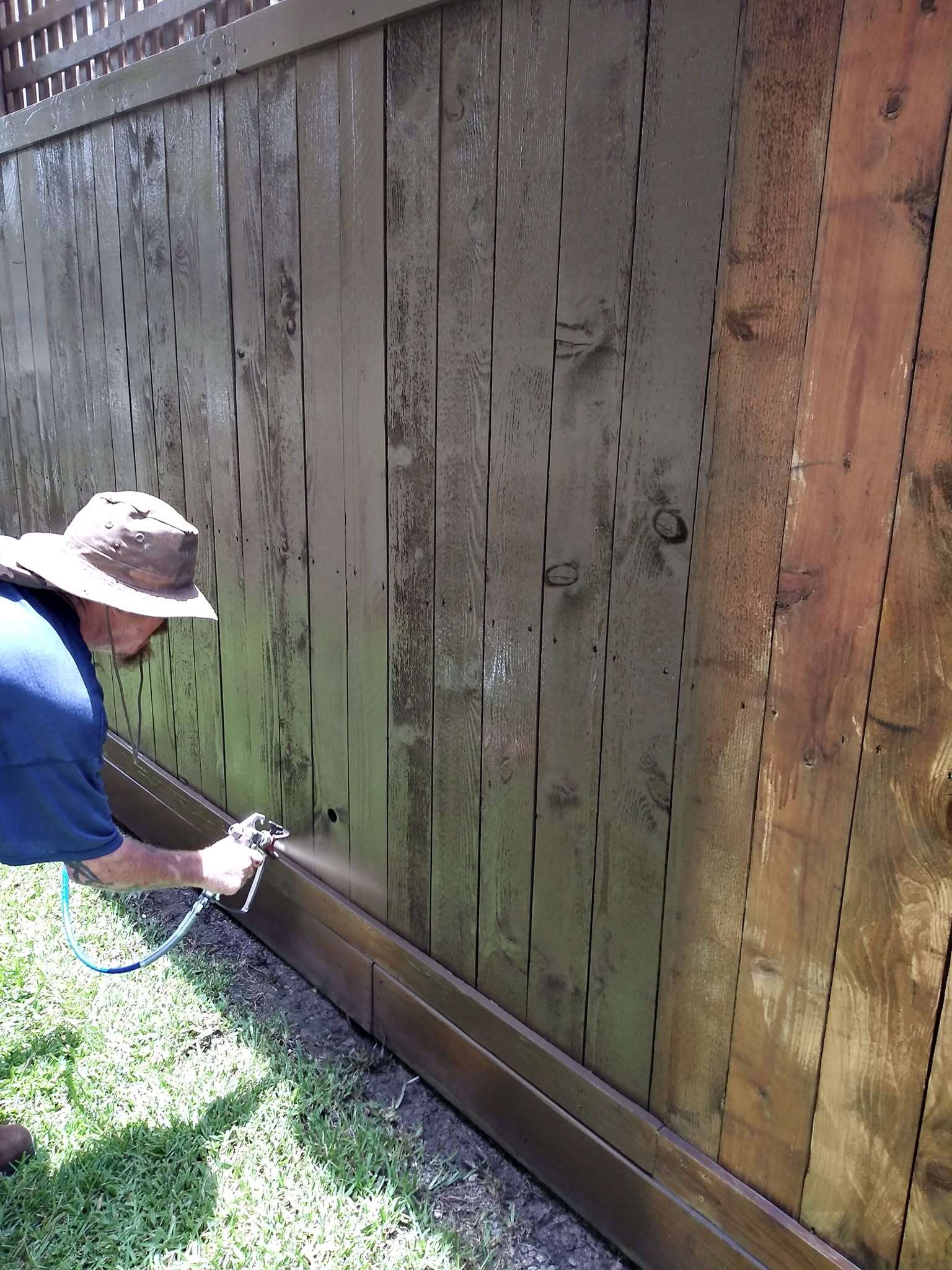 Professional applying stain to a residential wood privacy fence