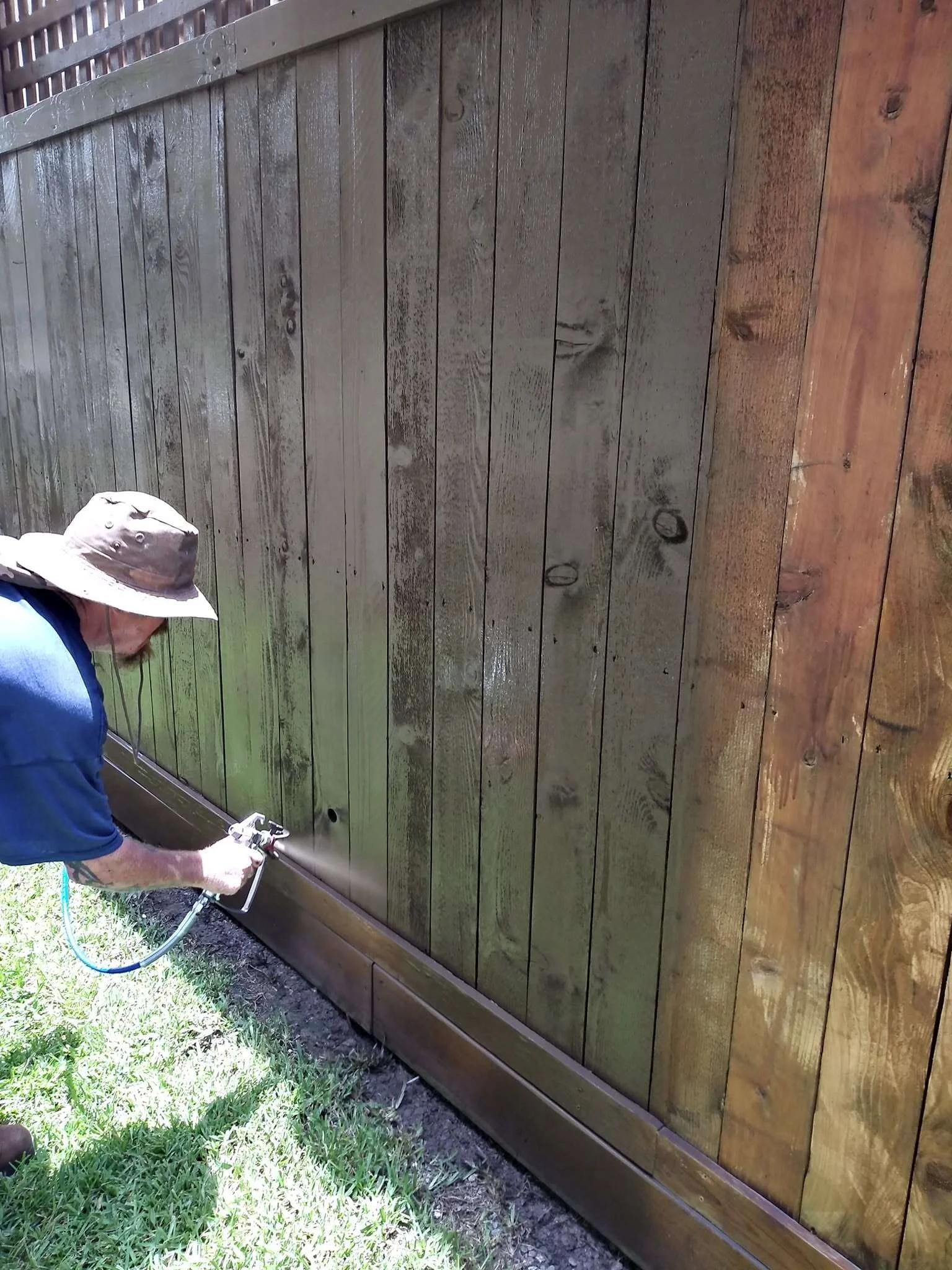 Professional applying stain to a residential wood privacy fence
