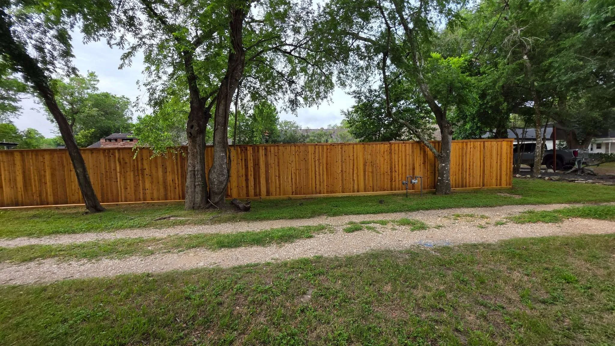 Long freshly stained cedar fence surrounding a large Houston-area property